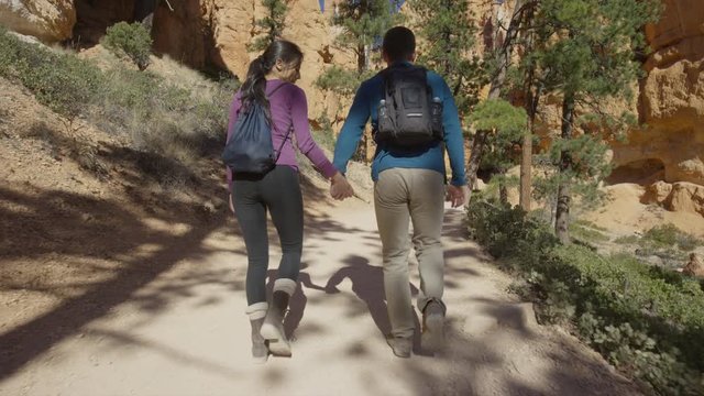 Medium slow motion tracking shot of couple hiking in desert / Bryce Canyon National Park, Utah, United States