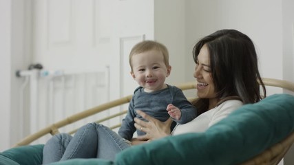 Medium shot of mother sitting holding baby son with tongue out / Provo, Utah, United States