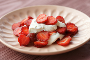 Sliced strawberries with sour cream on a plate
