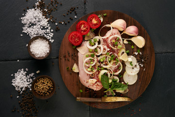 Top view of a chicken fillet for grilled, spices, tomatoes, mushrooms, onions on dark stone background. Raw meat chicken for cooking. Delicious balanced food concept. Healthy food, low-calories diet.