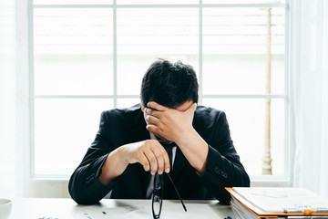 A stressed out business man holds his head in despair as he fears that he will have to file for...