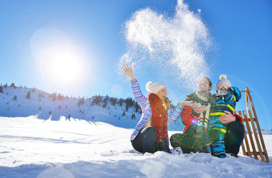 happy young family playing in fresh snow at beautiful sunny winter day outdoor in nature