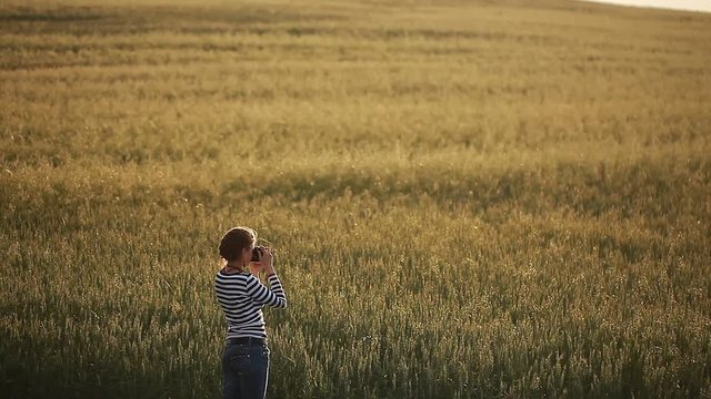 Young woman taking pictures in the field