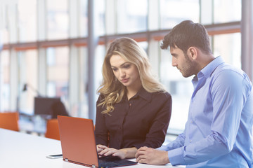 Young couple working together on a laptop in the office. Teamwork concepts.