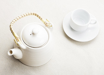 Set of white coffee mug and coffee maker on tablecloth.