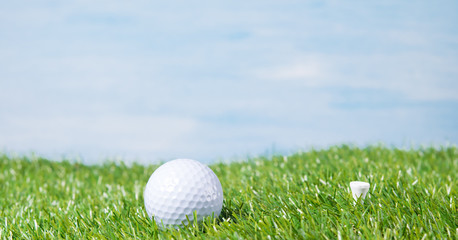 Golf ball against the sky and a green lawn