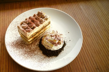 Tiramisu, traditional Italian dessert with whipping cream in  white plate on wooden table