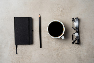 Office desktop with coffee cup, pencil, notebook and glasses