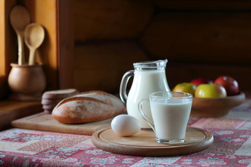 Village breakfast. A glass of milk, bread and fruit are on the table near the window in the rustic house.