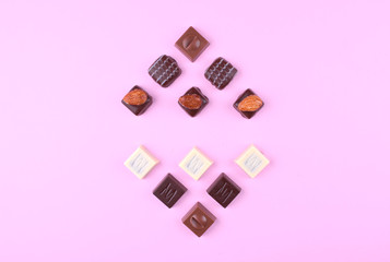 Various chocolate pralines on pink trendy background.