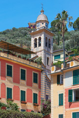 Fototapeta na wymiar Portofino typical colorful houses and Divo Martino church bell tower with palm tree, Italy