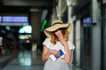 Pretty girl in a wide-brimmed hat with the passport and tickets in a hand.
