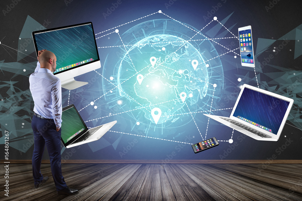 Poster businessman in front of a wall with computer and devices displayed on a futuristic interface with in