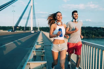 Fotobehang Attractive man and beautiful woman jogging together © NDABCREATIVITY