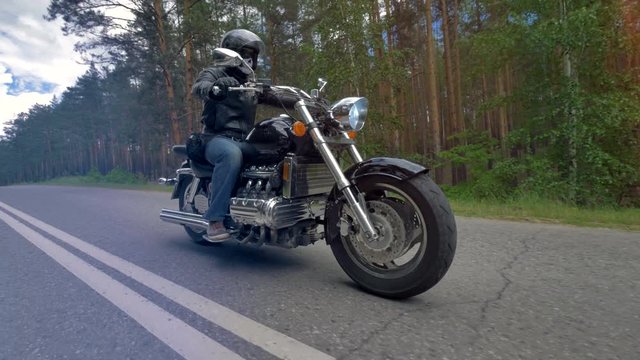 A biker riding a motorcycle wearing black clothes and helmet.