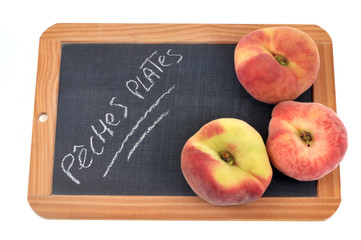 Pêches plates posées sur une ardoise 