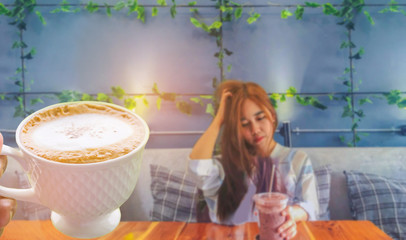 The abstract soft focus of young lady, teenage girl drink the cool coffee in the plastic glass in the room with the beam light, shadow, and lens flare effect tone background.