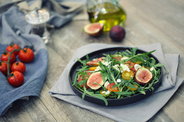 Fresh salad with arugula tomato and cheese on wooden background