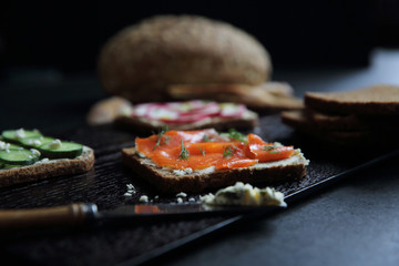 Sandwich with cereals bread smoked salmon beetroot and cucumber on dark marble background