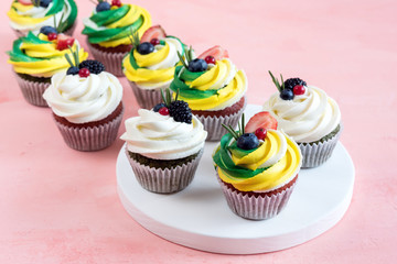 Tasty cupcakes with cream cheese topped with fresh berries Pink background Beautiful cupcakes decorated with colorfull cream cheese