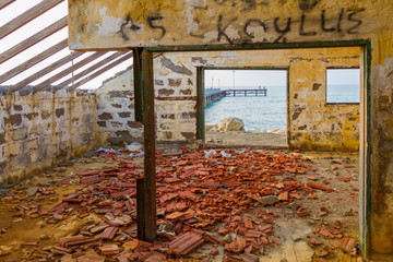 Pier view through derelict house by the beach