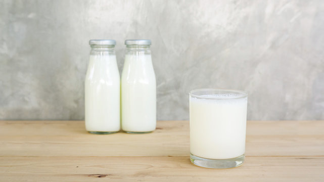 a bottle and glass of milk on a wooden table.