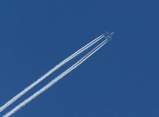 Aircraft and Diagonal Condensation Trails or Contrails on a clear blue sky