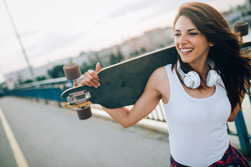 Portrait of beautiful smiling girl carrying skateboard