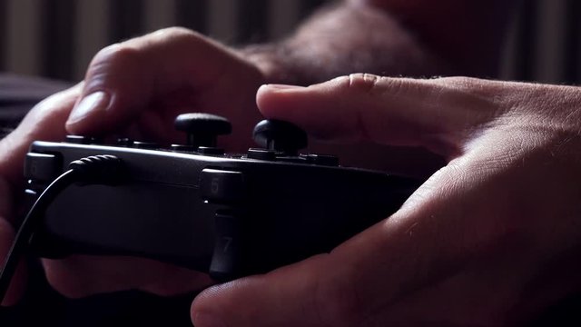Video game console controller in male hands, man playing entertaining game at home