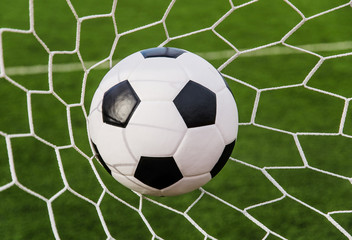 Obraz na płótnie Canvas Soccer football in Goal net with green grass field.