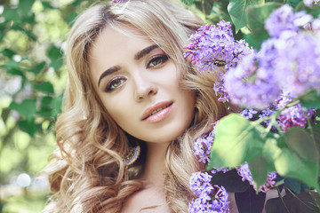 Outdoor fashion beautiful young woman surrounded by lilac flowers summer. Spring blossom lilac...