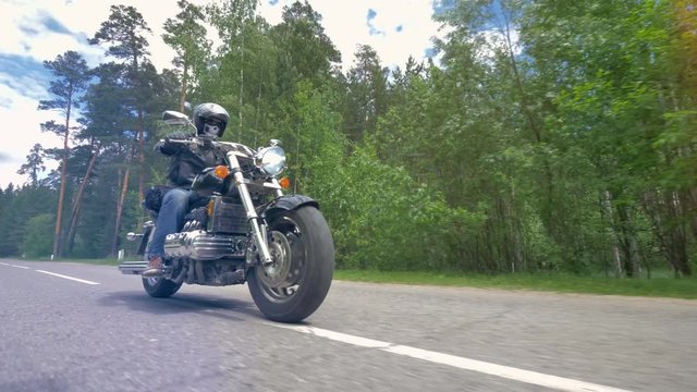 Enjoying motorcycle ride on empty road in forest.