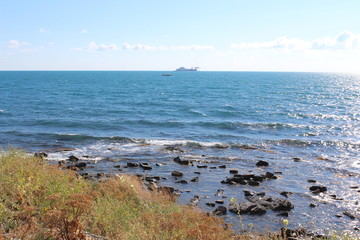 The Black Sea coast in a summer sunny day and the ship in the distance
