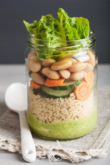 vegan couscous salad in mason jar with beans cucumber carrot and avocado dressing