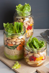vegan couscous and pasta salad in mason jars with vegetables beans