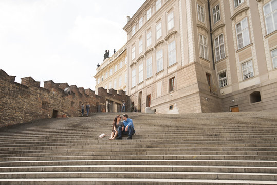 Happy beautiful loving couple is sitting on the strais in Prague.