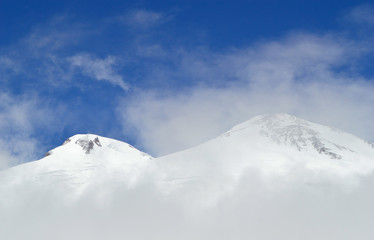 Fototapeta na wymiar Head of Elbrus mountain viewed through fog and clouds