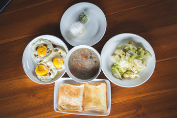 Rice porridge with pork,fried egg and toast thai breakfast on wooden table.At 