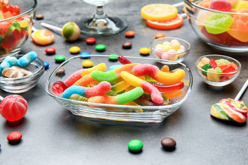 Bowls with delicious candies on grey background
