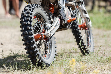 Fototapeta na wymiar Close-up of muddy rear wheel and engine of dirt motorcycle