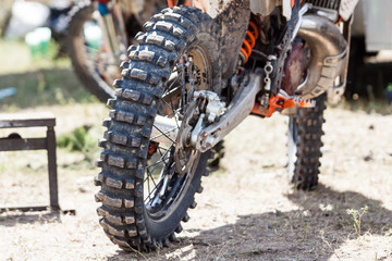 Close-up of muddy rear wheel and engine of dirt motorcycle