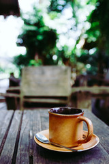 Cup of coffee on the wooden table in cafe. Films grain filter.