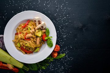 Pasta with chicken fillet, parmesan cheese and mushrooms and basil. On a black wooden surface. Free space for your text. Top view.