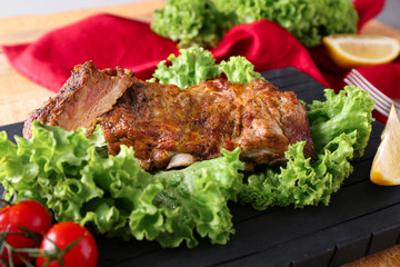 Yummy grilled spare ribs with fresh salad leaves on black board