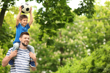 Obraz premium Dad and son with soccer ball in green park