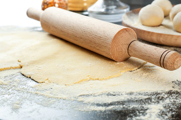 Unleavened dough for tortillas with rolling pin on kitchen table
