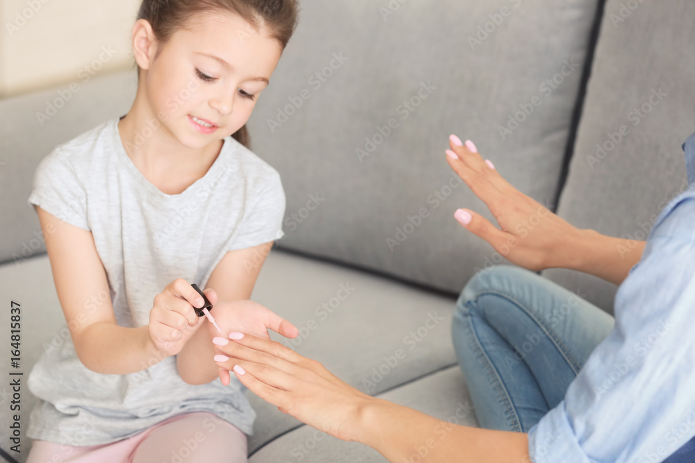 Sticker Young woman and her little daughter doing nails at home