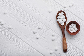 white medical pills on wooden spoon