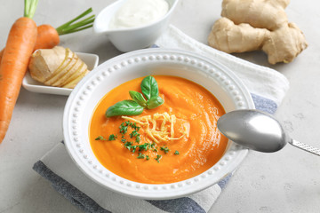 Composition with delicious carrot soup and fresh ginger on table