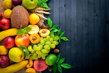 Big set of fresh fruit on a black wooden table. Free space for your text. Top view.